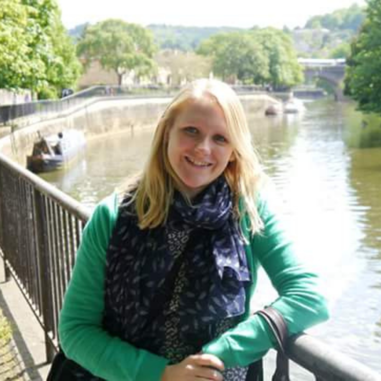 Photograph of Cathy standing by a river in the sunshine
