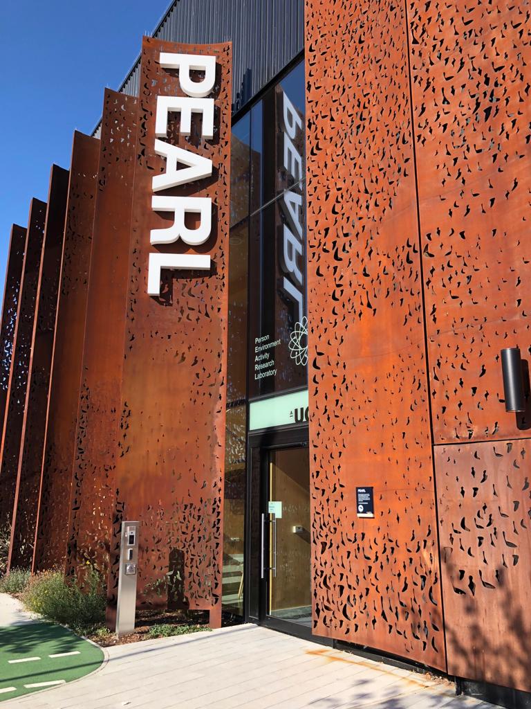 Copper coloured building with the word PEARL written on the side. In the centre is a glass door to access the space as well as an intercom buzzer